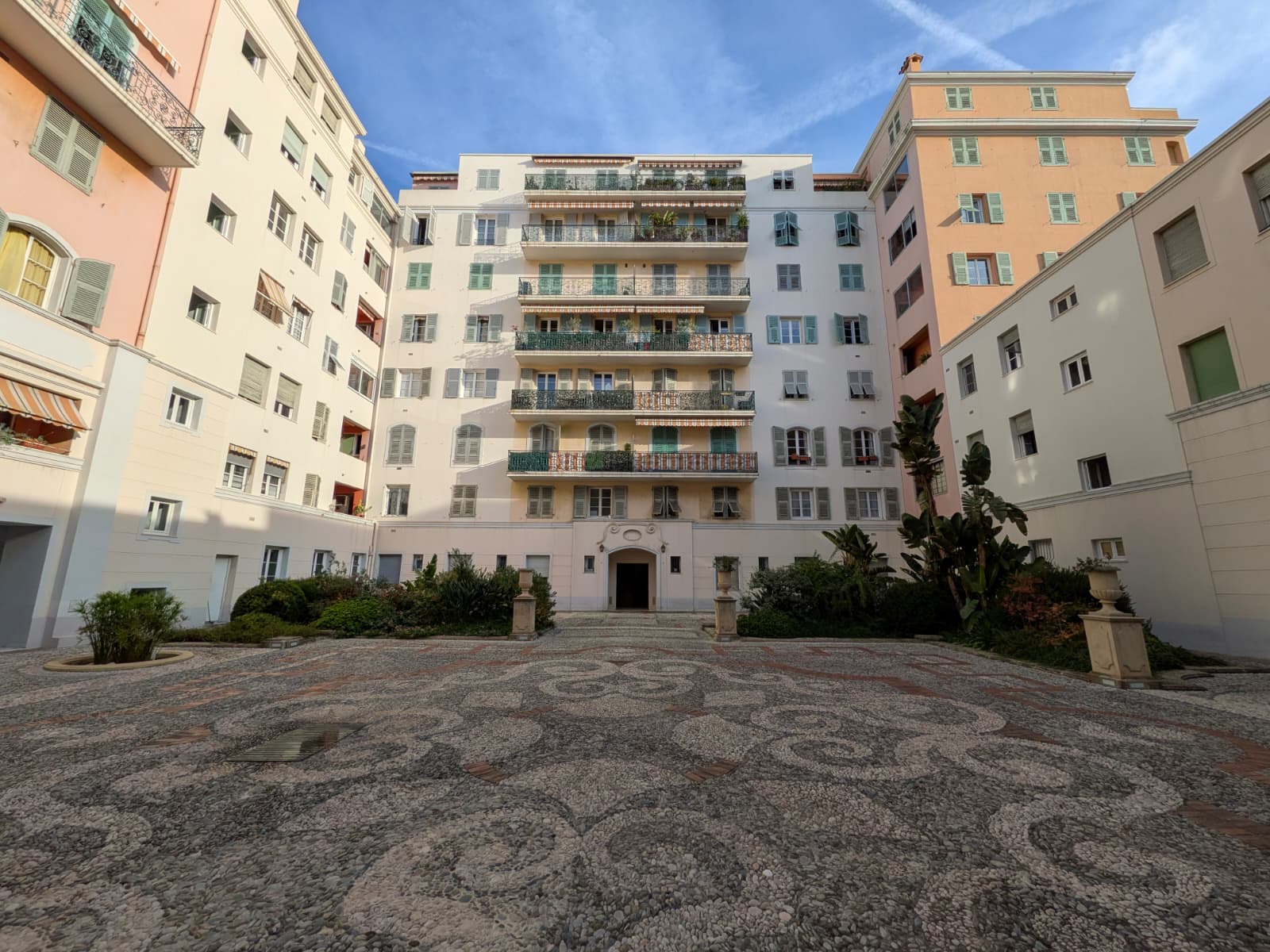 The patio of Le Neptune on the port of Nice: pebble calade paving, renovated façades and arched entrance