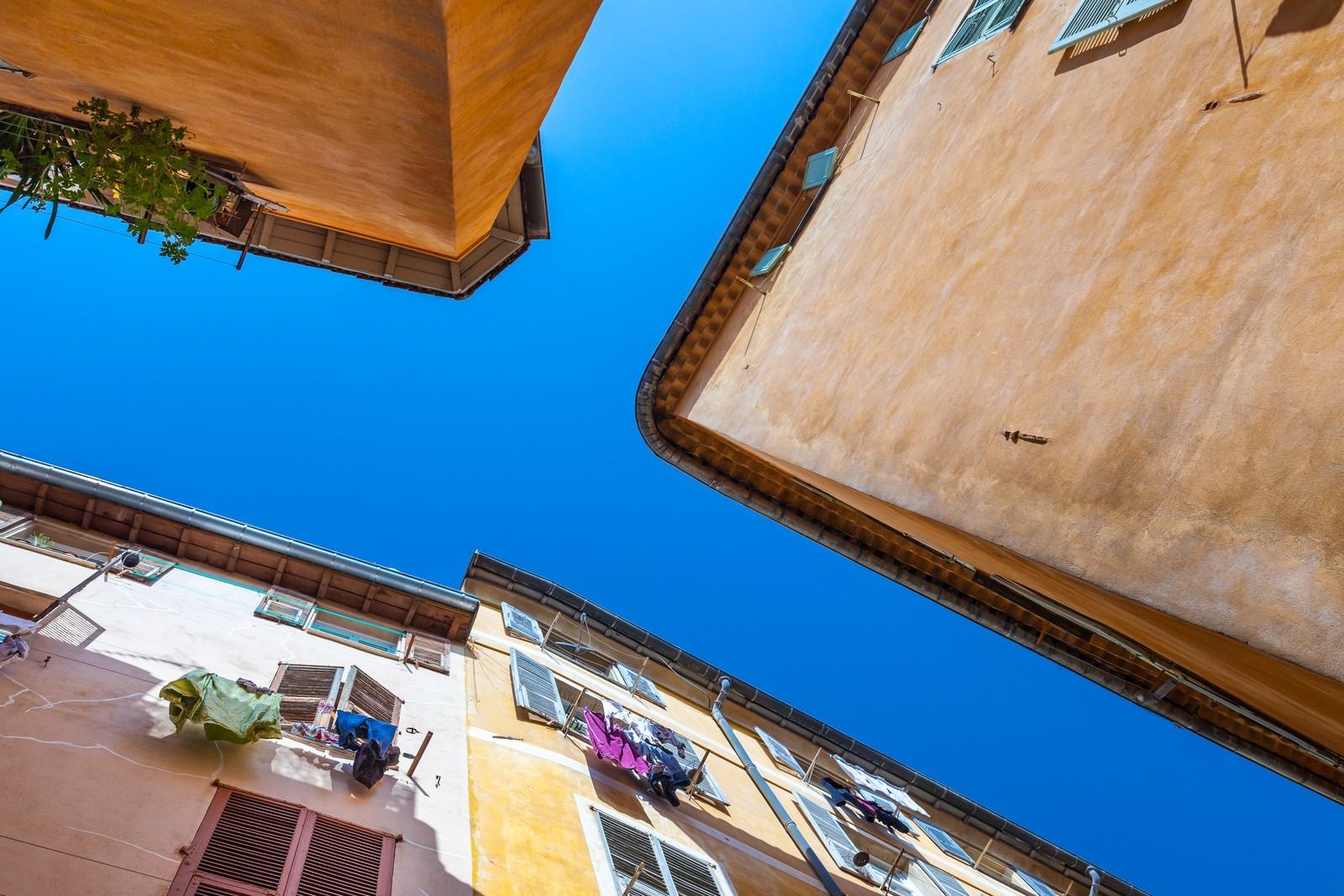 Ochre façades and shutters in a lane of Old Nice, seen from below